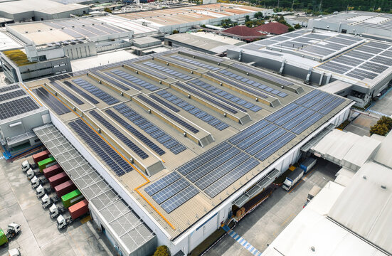 Solar-powered warehouse facility with freight trucks at loading docks. Eco-friendly logistics and efficient cargo transportation. Solar panels and sustainable energy concept in distribution center.