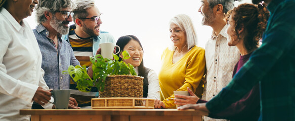 Group of multigenerational people having fun during job coffee break - Multiracial colleagues of different ages having fun together inside office relax space  - Main focus on asian girl face