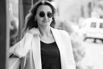 Elegant Woman in Fashionable Attire Posing Outdoors with Sunglasses