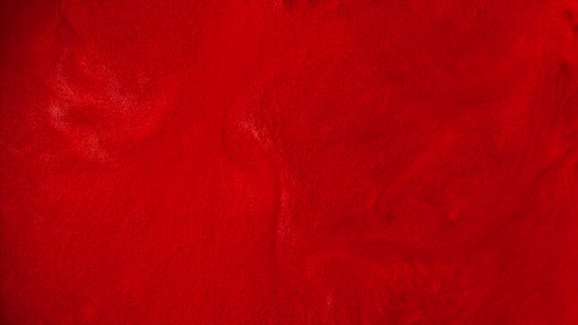 Flowing red abstract glitter background. Liquid paint moves in waves and swirls. Beautiful shiny red texture with sparkles. Metallic paint in motion. Shimmer in slow motion.