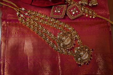 multiple gold chain and necklaces placed on red silk saree. indian Bridal gold jewelry collection. antique gold jewellry