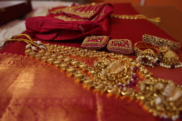 multiple gold chain and necklaces placed on red silk saree. indian Bridal gold jewelry collection. antique gold jewels