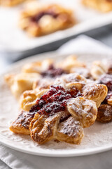 Sweet dessert pastries made of puff pastry with strawberry jam filled with caramelized apple sprinkled with powdered sugar