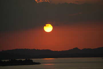 Obraz premium Beautiful sunset stunning sunset descends gracefully behind the rugged mountains, casting warm hues across the landscape. The river below mirrors the vibrant colors, turning