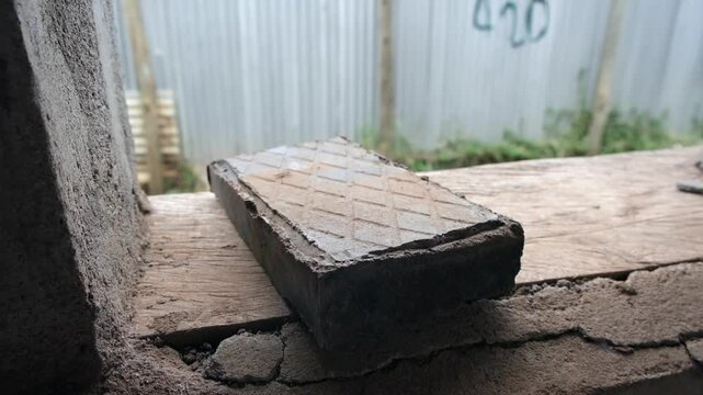 Close-up of a brick made from recycled plastic, placed on a rough surface