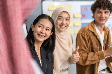 Obraz premium Diverse team young professionals brainstorming and collaborating in modern office, sharing ideas and positive feedback with focus on teamwork and project planning, smiling colleagues at a meeting