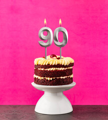 Birthday cake with number 90 candle - Red velvet on a fuchsia background.