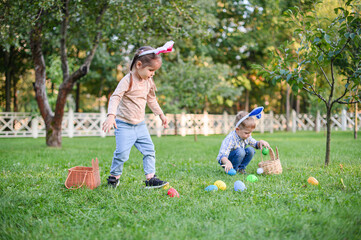 Children Collecting Easter Eggs Outdoors in Bunny Ears