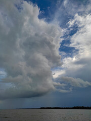 A view of thick clouds pouring heavy rain over the land and river below, creating a misty atmosphere.