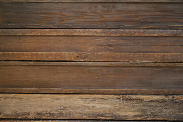 A brown background of wooden boards arranged horizontally. The boards are slightly worn, which adds a feeling of naturalness and antiquity. Ideal for backgrounds in designs, advertisements