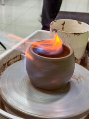 A pottery wheel with a clay vase in the firing process. Flames create a dramatic scene of creativity. A masterclass on creating ceramics using traditional techniques.