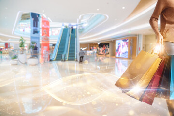 A shopper walks through a large, modern shopping mall with a blurred background and bokeh lights.