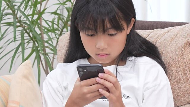 リビングでスマホを見ている女子中学生