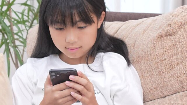リビングでスマホを見ている女子中学生