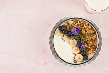 A healthy nutritious breakfast of natural Greek yoghurts, granola and fresh berries on pink background. Copy space