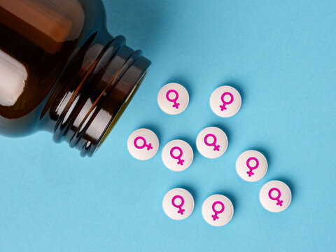 Medical hormone pills with female symbol spilling out of the bottle.