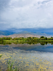 Obraz premium A quiet mountain lake Issyk-Kul, surrounded by green valleys and majestic mountains. The perfect spot for tourism and peaceful relaxation in Kyrgyzstan.