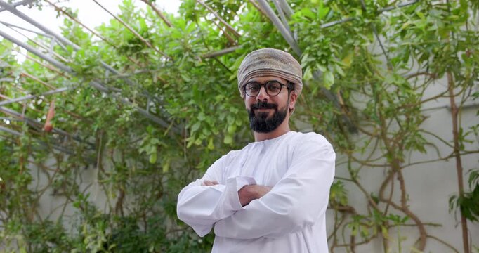 Omani man wearing dishdasha and Musaar is stand folding his arms