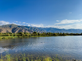 Fototapeta premium A quiet mountain lake Issyk-Kul, surrounded by green valleys and majestic mountains. The perfect spot for tourism and peaceful relaxation in Kyrgyzstan.