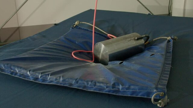 A heavy mass falls from above in slow motion and crushes a mattress, laboratory experience
