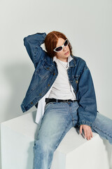 A teenage boy with vibrant red hair poses confidently in a stylish denim ensemble in a studio.