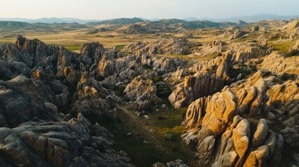 Aerial view of rugged, rocky terrain with sparse vegetation under a clear sky.