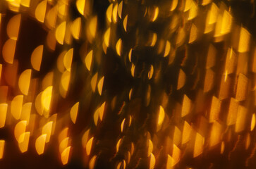 Abstract golden bokeh lights create a shimmering atmosphere in a festive setting during the evening hours