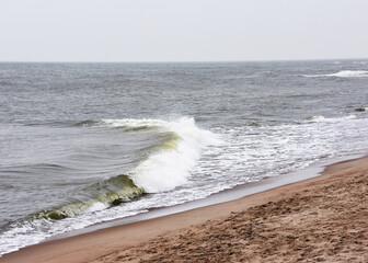Waves are crashing on a beautiful sandy beach on a cloudy day