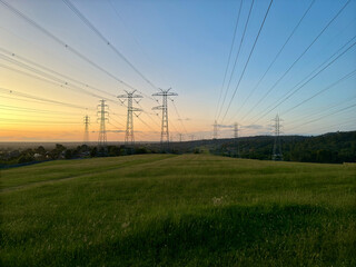 Neighbourhood powerlines at nature field during sunset