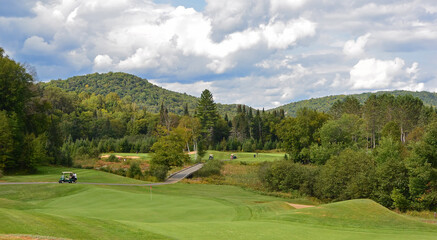 A green golf course among the rolling hills with a cloudy sky on a beautiful summer day in Canada