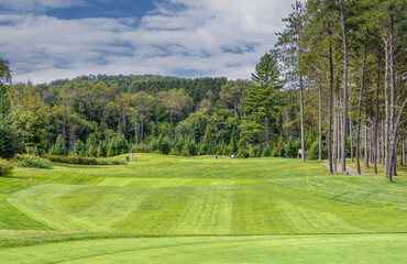 A green golf course among the rolling hills with a cloudy sky on a beautiful summer day in Canada