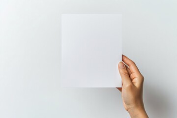 Obraz premium A clean, blank sheet of paper held in a hand against a minimalist background, perfect for showcasing creativity or starting a new project.