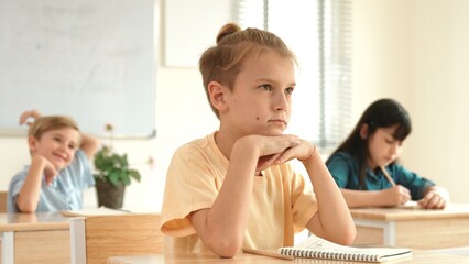 Smart elementary student looking at teacher while attend in classroom. Diverse smart student sitting at classroom while listening teacher explain about classwork or test. Education concept. Pedagogy.