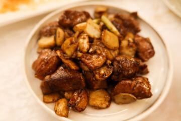 close up of stir pan-fried beef cubes with garlic slice on a white plate in Chinese restaurant