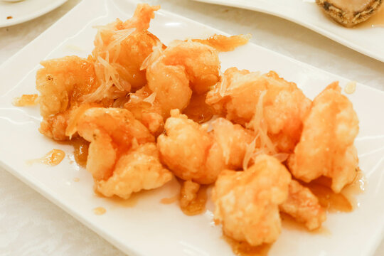 Close up of Chinese Cantonese deep fried prawns shrimps with citrius sauce on a white plate