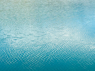 Clear water with soft waves on the surface, creating a beautiful pattern. Natural purity and calmness of water.