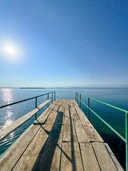 Obraz premium A wooden pier on Issyk-Kul lake with a view of the mountains. A beautiful spot for relaxation and enjoying the natural landscapes of Kyrgyzstan