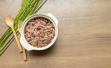 Cooked Brown Rice blend in Ceramic Bowl with Wooden Cutlery on Wooden Table