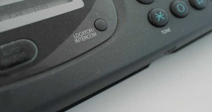 Close-up, finger pressing locator intercom button on an old fax machine, analog transmission of information. Concept of search for telephone handset, device on the network.