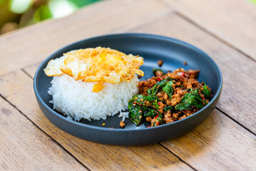Spicy fried pork with basil leaves, the famous traditional Thai food served with jasmine rice and...