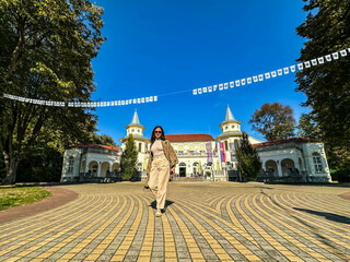 A brunette walking towards the camera, in the background  famous Kur salon in the famous Serbian spa Banja Koviljaca  