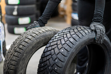 Fototapeta premium Mechanic keeps new summer and winter car tires in the garage. Comparison of wheels for different seasons. 