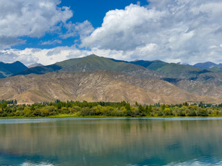 A wooden staircase leading into the clear waters of Issyk-Kul lake, with visible underwater vegetation. A perfect spot for water relaxation and enjoying nature