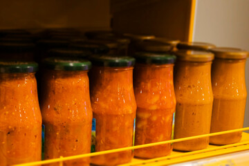 Jars of tomato sauce are organized on a refrigerator shelf