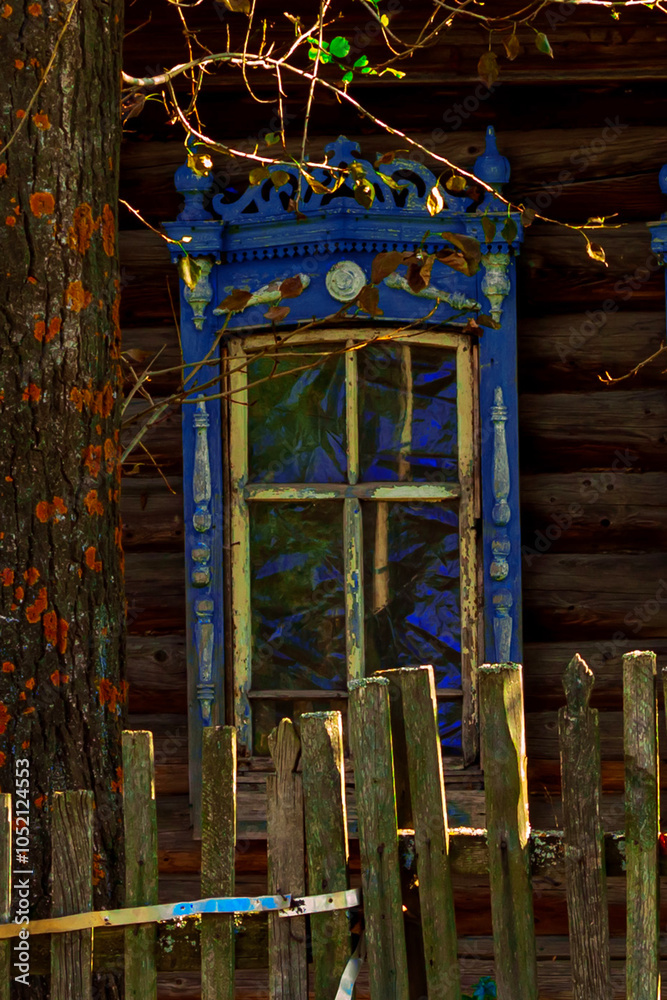 Wall mural Old houses. Carved window frames. View of a fragment of a house wall with carved decorations around the window and doors. Traditional Russian old houses. Close-up. Front view. Landscape.