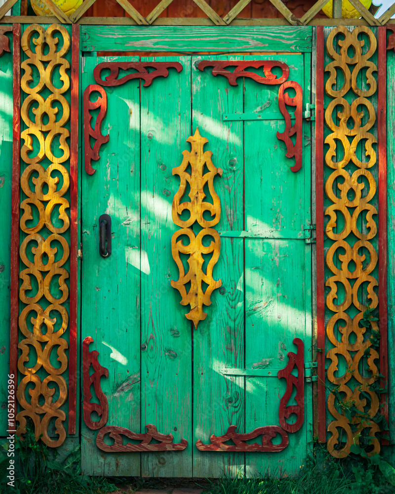 Wall mural Old houses. Carved window frames. View of a fragment of a house wall with carved decorations around the window and doors. Traditional Russian old houses. Close-up. Front view. Landscape.