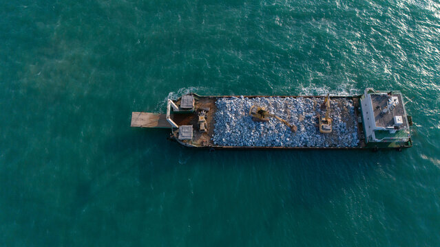 A ship is carrying a backhoe in the sea.
