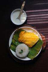Mango sticky rice, a popular Thai dessert. The plate features beautifully sliced, ripe golden...