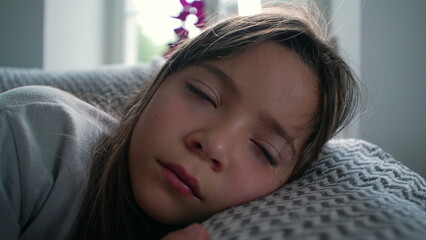 Young girl lying on the couch, head resting on a cushion, gazing thoughtfully into the distance, conveying a sense of introspection, quiet reflection, and daydreaming