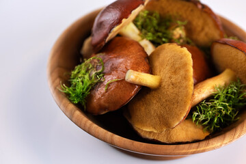 Suillus granulatus mushroom in a wooden bowl on white background. Weeping bolete.